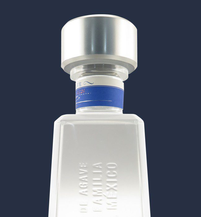 Close up photograph of an 1800 silver proximo spirits tequila bottle, showcasing Cpg packaging production expertise through the use of metallic inks, embossed features and distinctive packaging design.