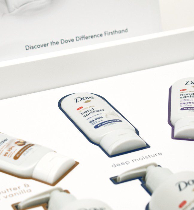 Close-up shot of the inside of an unboxing experience sales kit promoting skin moisturizing Dove hand sanitizer.