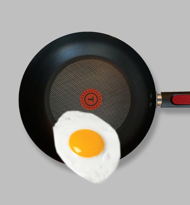 Close up photograph of a T-fal pan frying an egg.