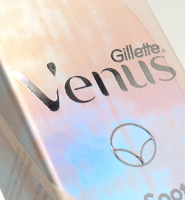 Close up photograph of the premium metallic foil effects on venus pubic hair razor packaging, created by a product packaging design agency.