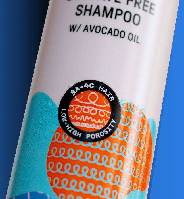 Close up photograph of a bottle of shampoo from the next of us hair products line, showcasing packaging design services for consumer packaged goods