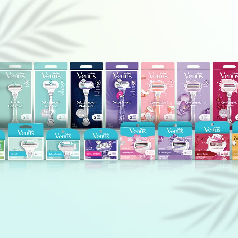 Photograph of a full product line of Gillette Venus comfortglide and deluxe smooth razors and cartridges, featuring packs created by a cpg packaging design agency.
