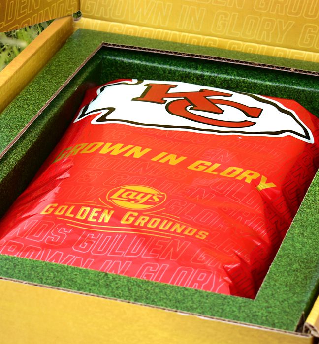 Close-up shot of a consumer sweepstake prize box for Lays Golden Ground, opening up to reveal limited edition packaging themed around an NFL team inside.