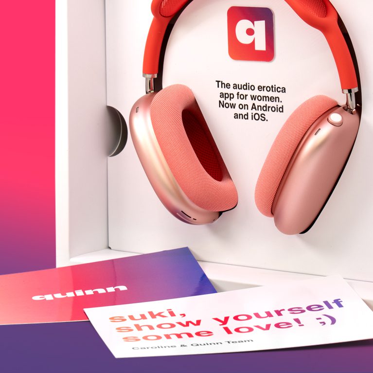 Photograph of the pink Quinn headphones inside an Influencer Unboxing Experience for the Quinn app, with a custom printed note on a gradient.